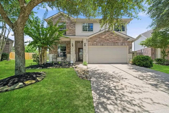 Two-story brick home framed by a mature tree on Whittmore Fields Dr