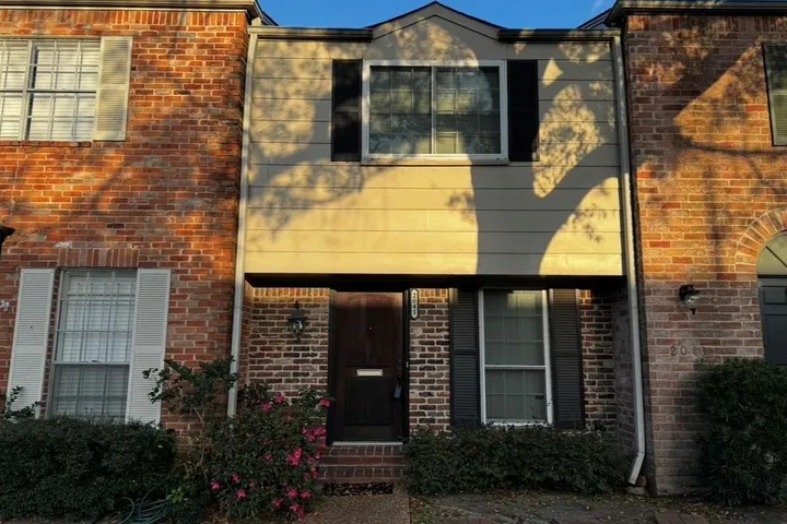 Two-story brick townhome with a dark wood front door on Winrock Blvd